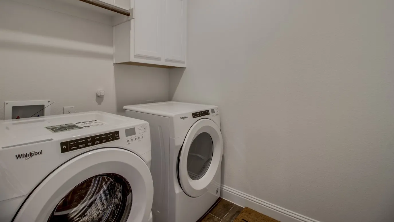 Dedicated laundry area featuring white cabinetry for storage