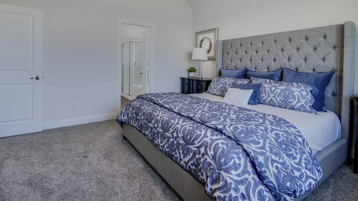Carpeted bedroom with a paneled door, offering access to a bathroom with a glass-enclosed shower