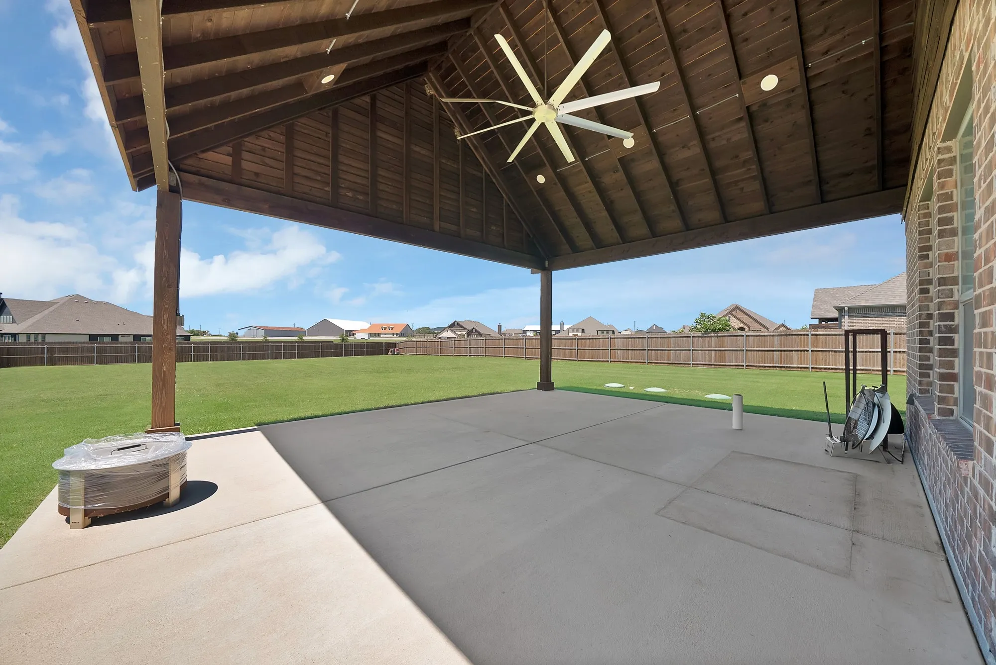 Expansive covered patio with a vaulted wood-finish ceiling, recessed lighting, and a large ceiling fan