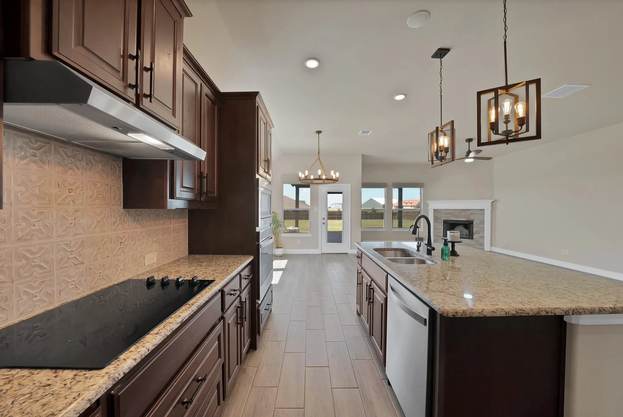 Spacious kitchen featuring dark wood cabinetry, granite countertops, an electric cooktop, and a decorative tile backsplash