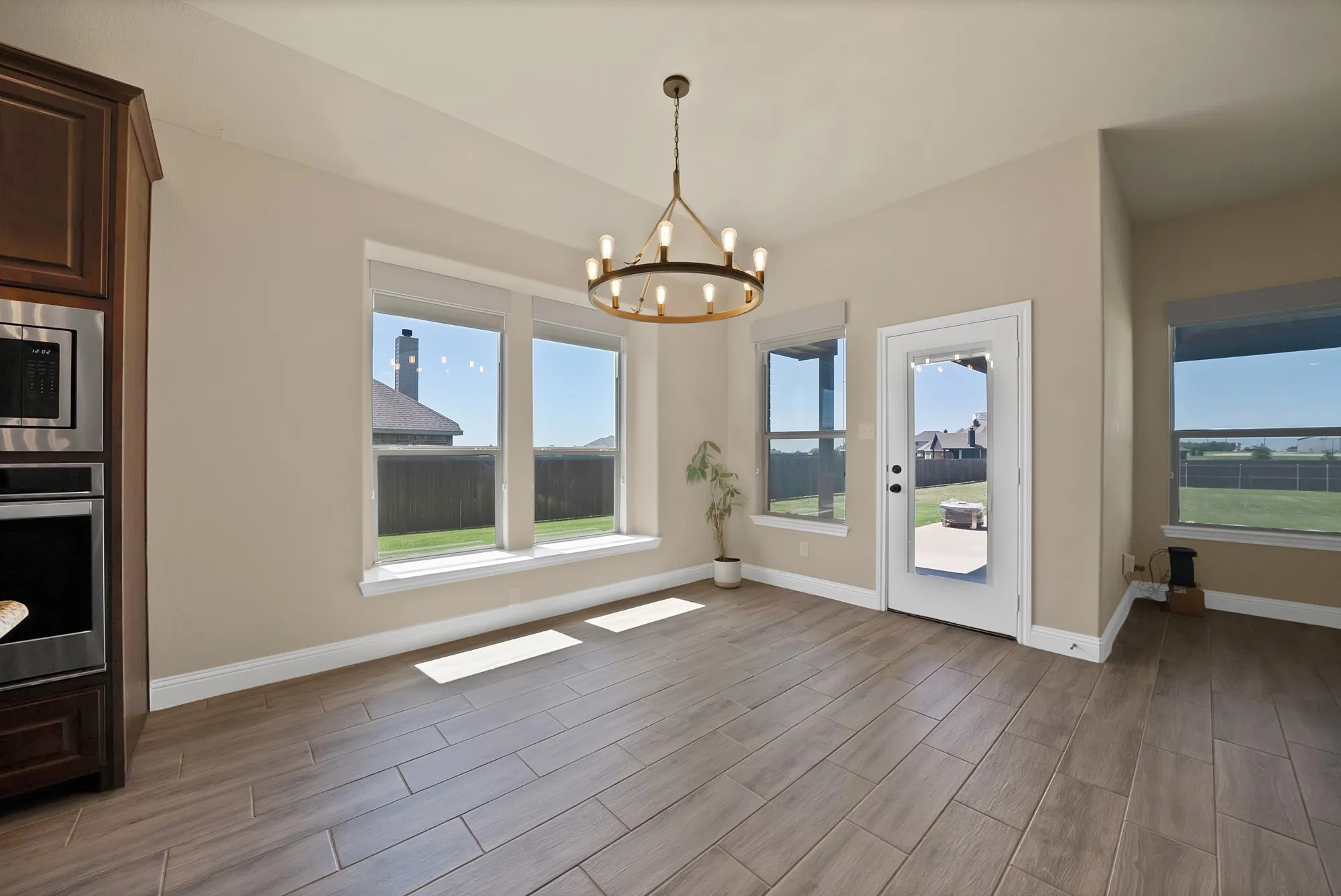 Spacious dining area featuring wood-finish flooring, a modern circular chandelier, and a built-in oven and microwave unit