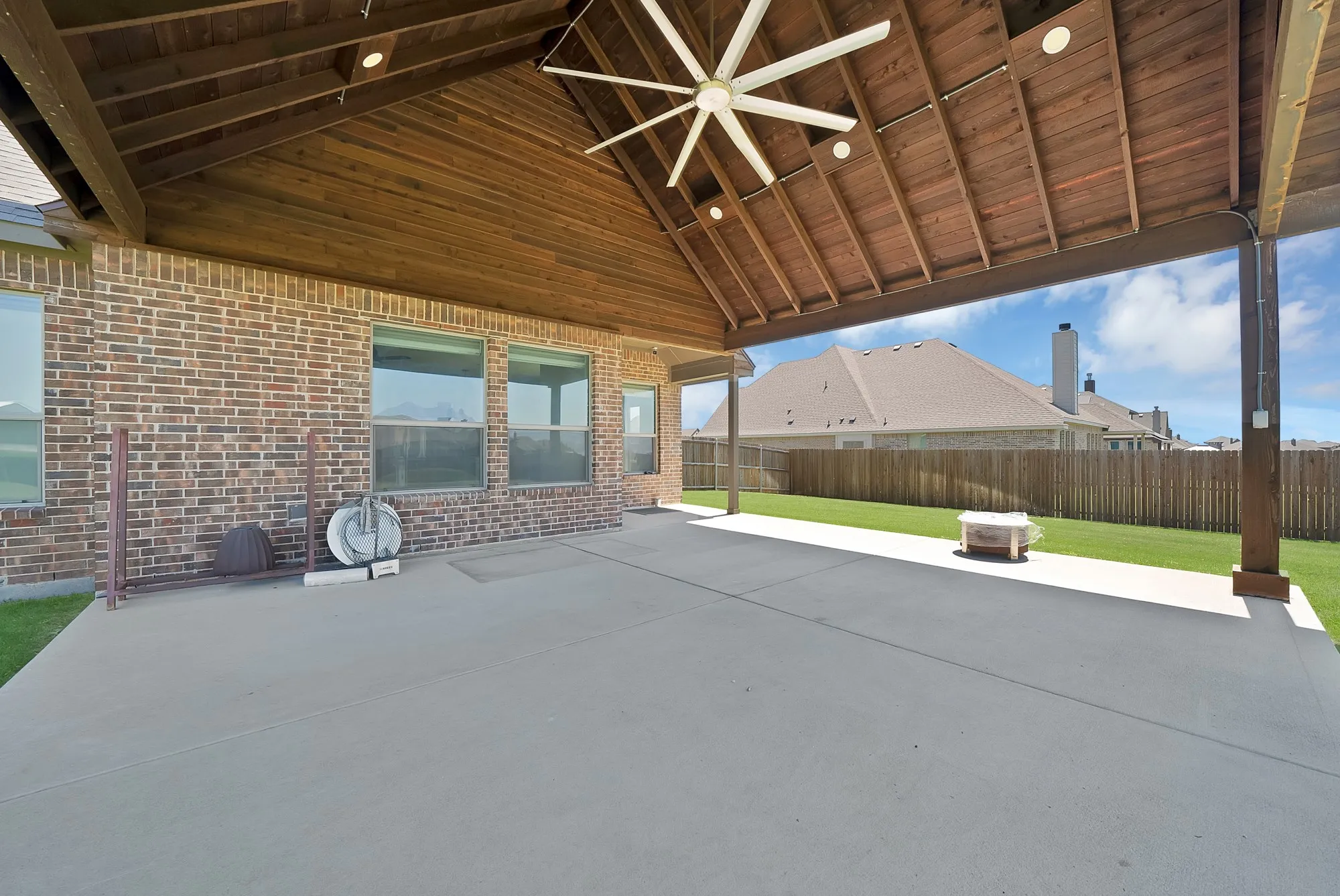Expansive covered patio featuring a vaulted wood-paneled ceiling with recessed lighting and a large ceiling fan