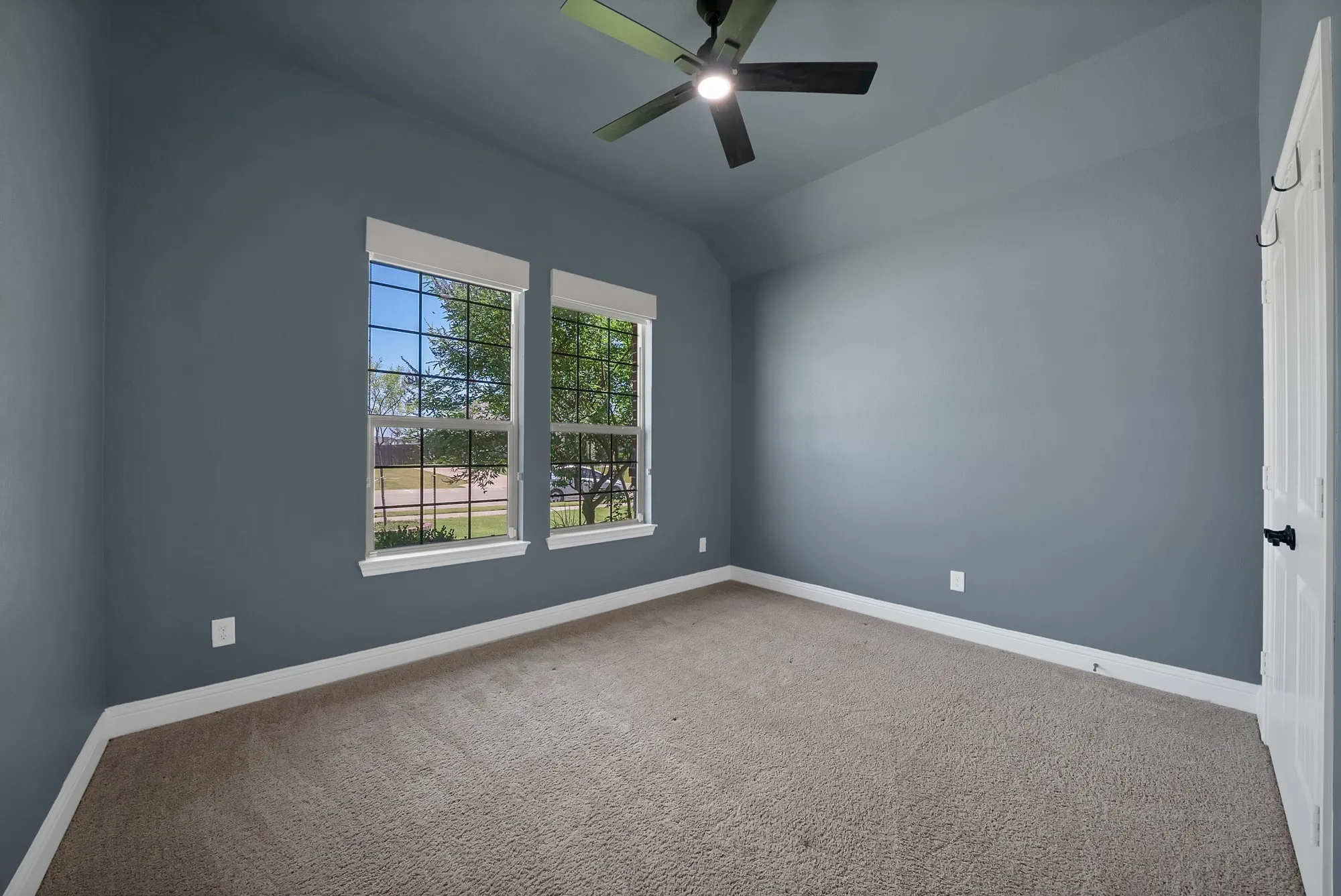 Room featuring light blue-gray walls, neutral carpeting, and white baseboards