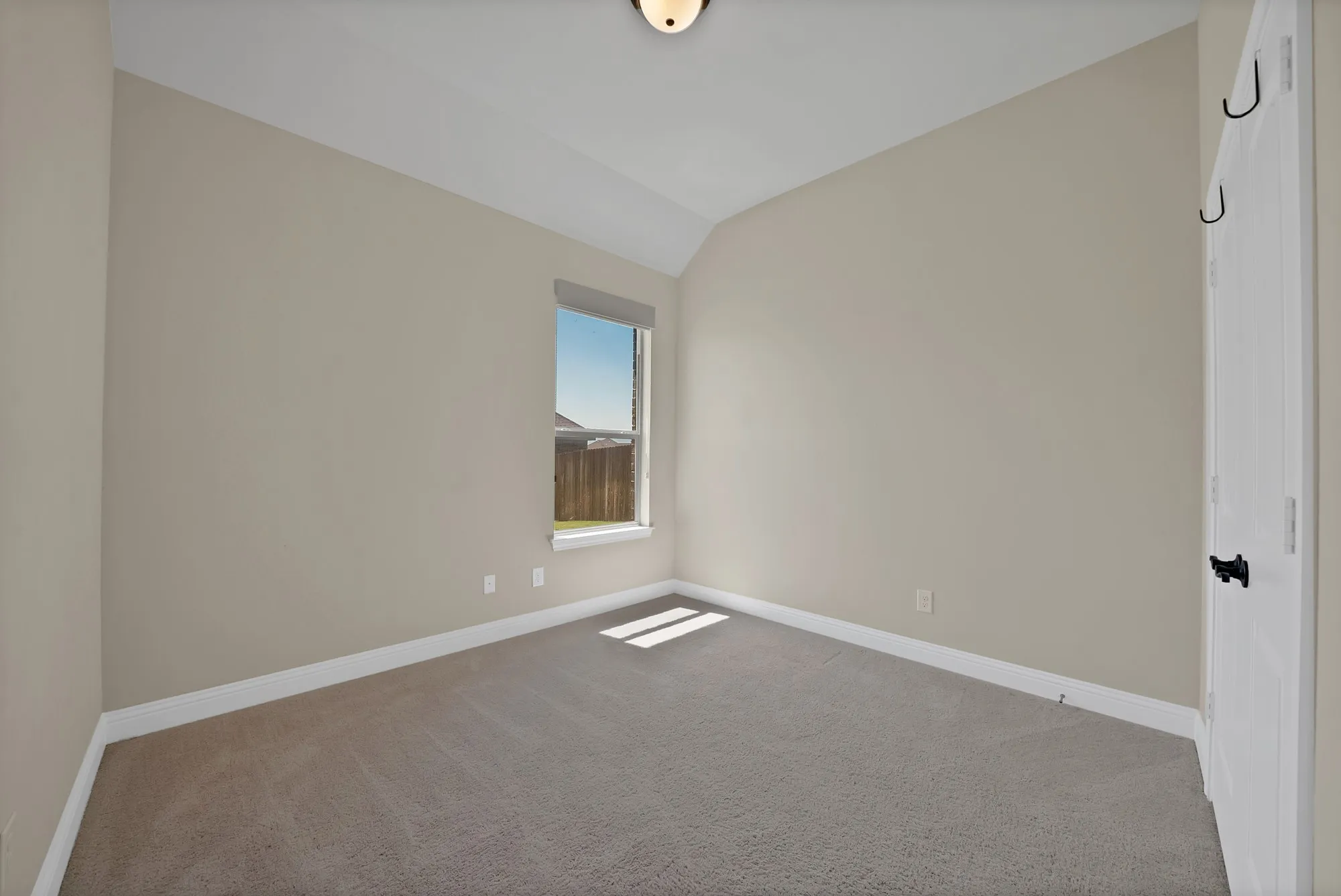 Carpeted room featuring a single window, neutral wall paint, white baseboards, and a ceiling light fixture