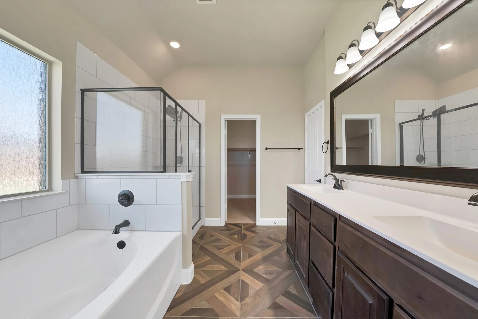 Contemporary bathroom featuring a freestanding tub, a glass-enclosed shower with subway tile surround, and a dual-sink vanity with white countertops and dark wood-finish cabinetry