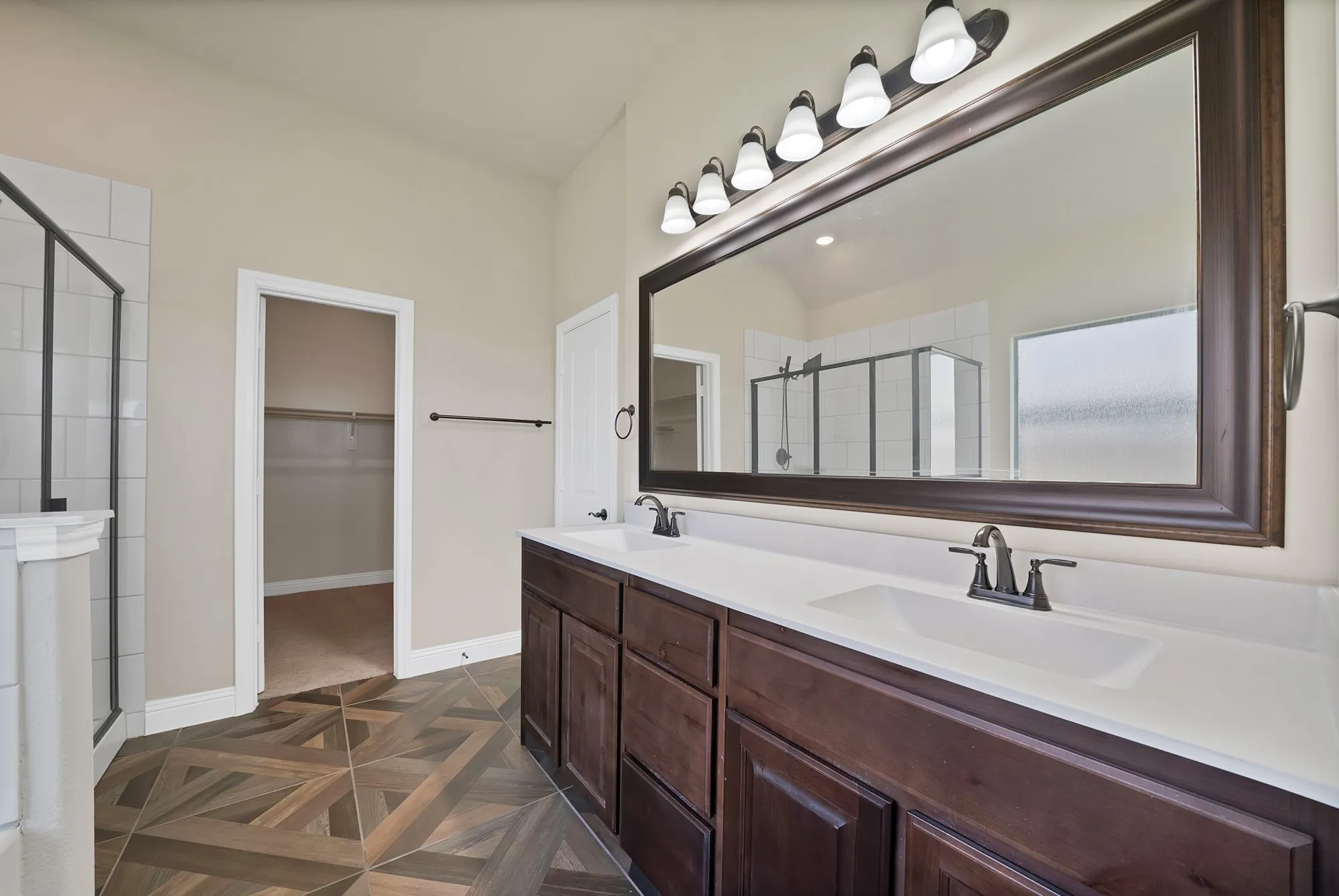 Dual vanity with white countertops, dark wood cabinetry, and oil-rubbed bronze fixtures