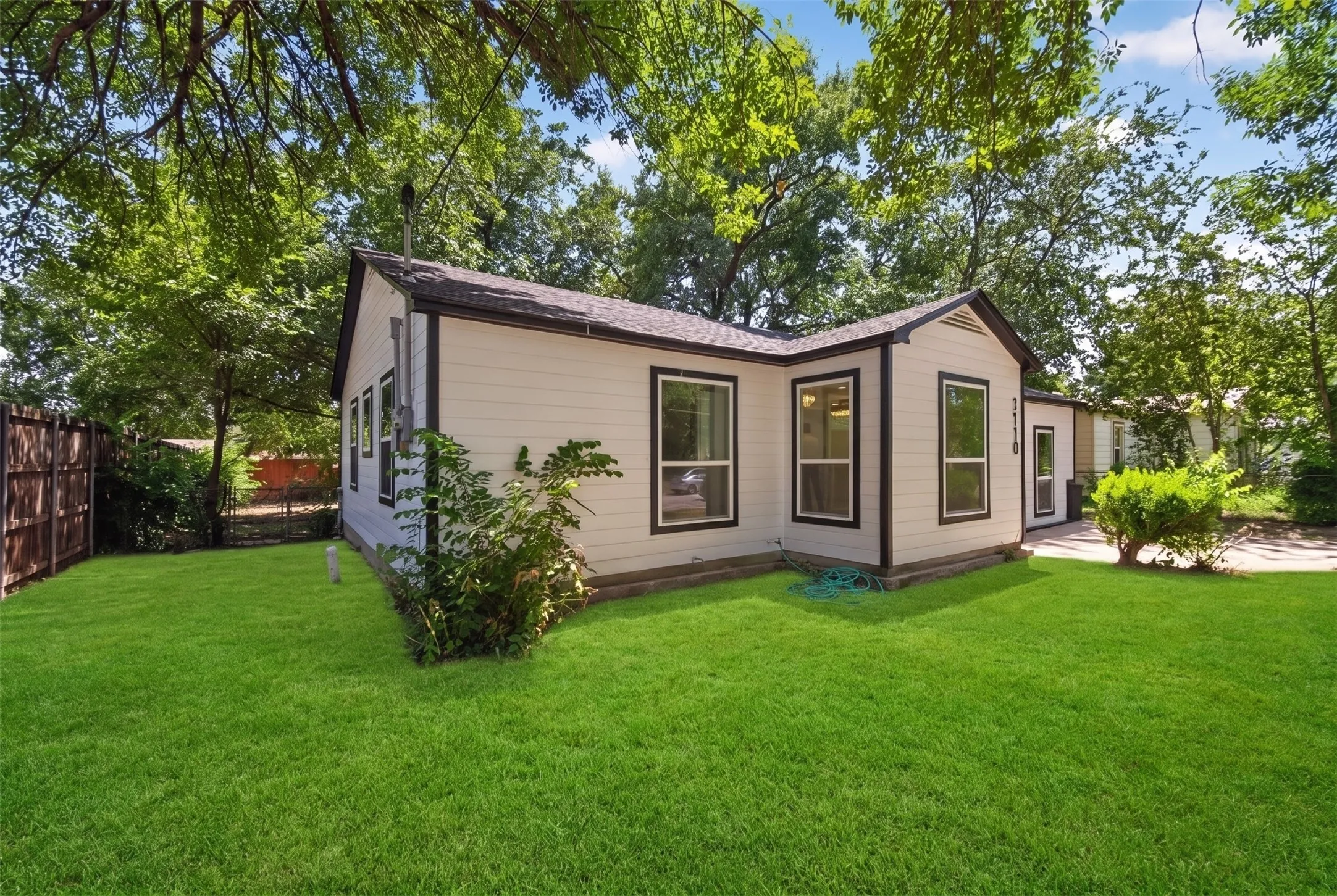 Exterior featuring light-colored siding with dark trim, multiple windows with dark frames, and a dark shingle roof