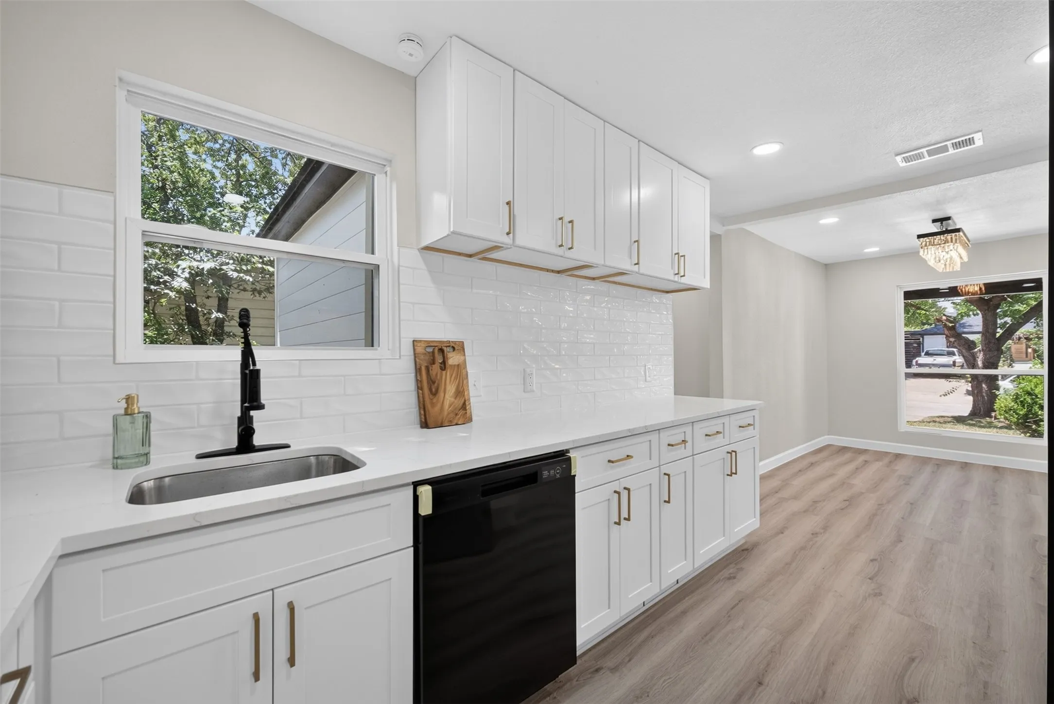 Modern kitchen featuring white cabinetry with gold-tone hardware, white quartz countertops, and a subway tile backsplash