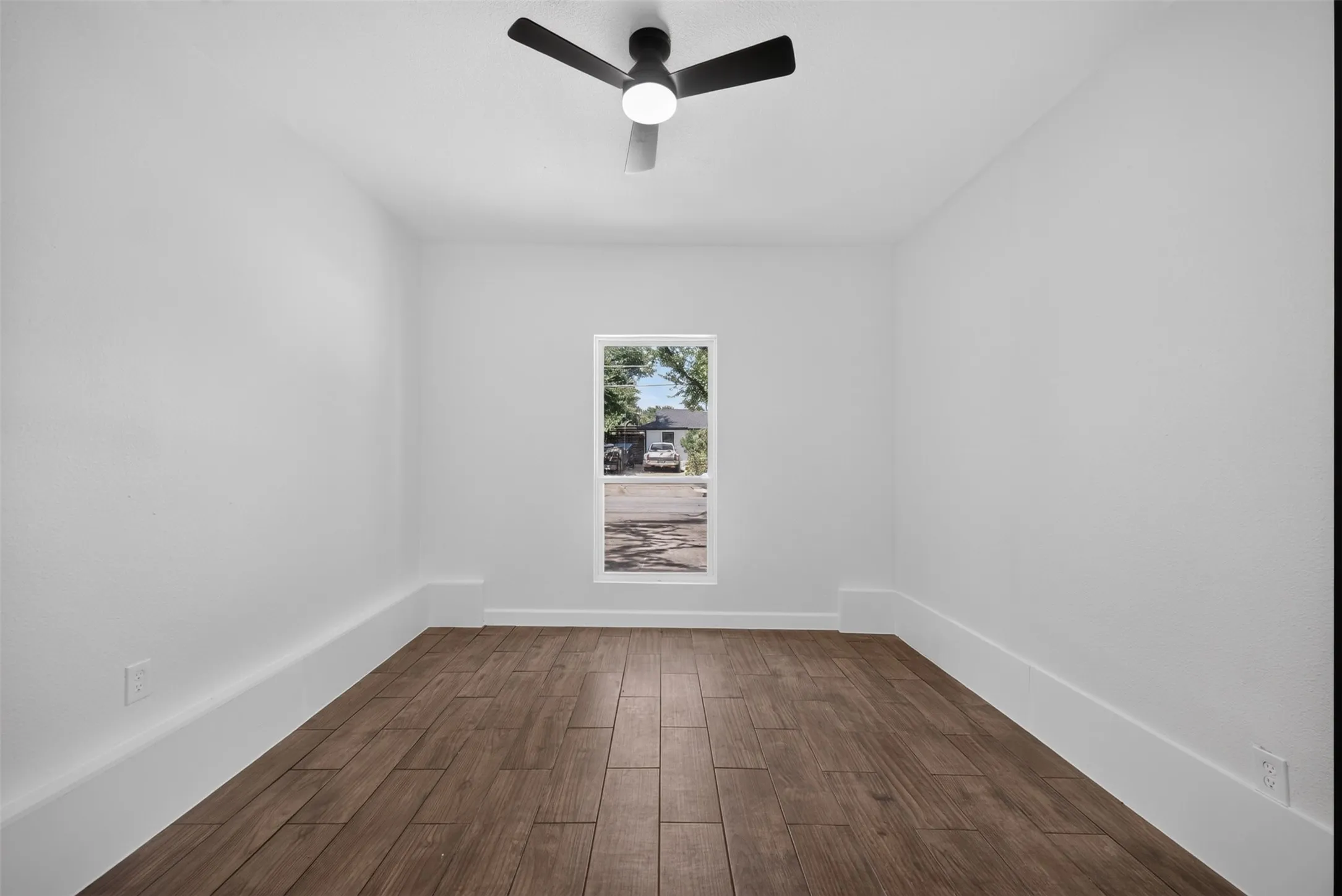 Bright room featuring wood-finish flooring, a contemporary ceiling fan, and white baseboards