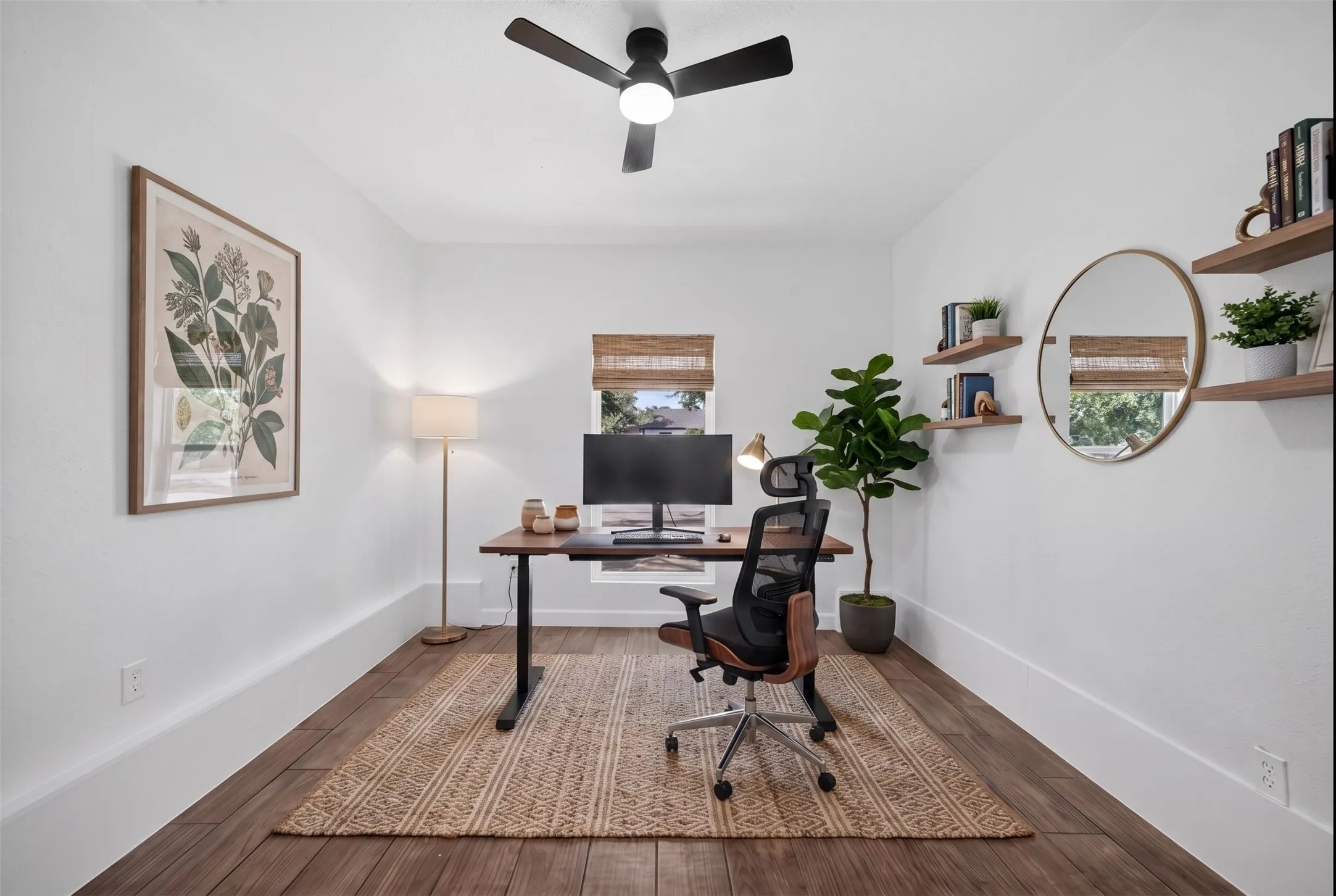 Hardwood-finish flooring featuring a woven rug, a ceiling fan with integrated lighting, and high baseboards