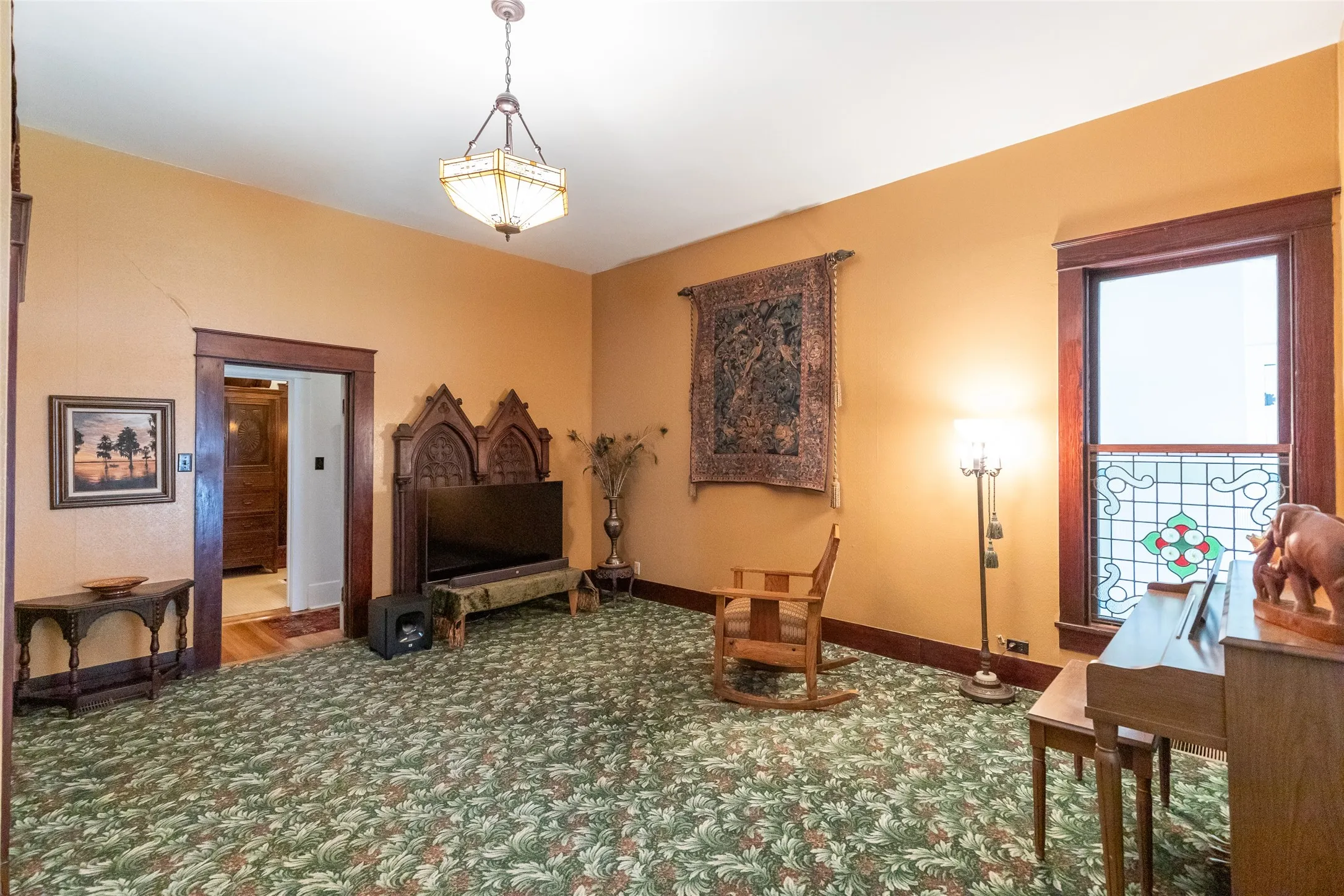 Spacious interior room featuring patterned carpeting, warm-toned walls, and dark wood trim