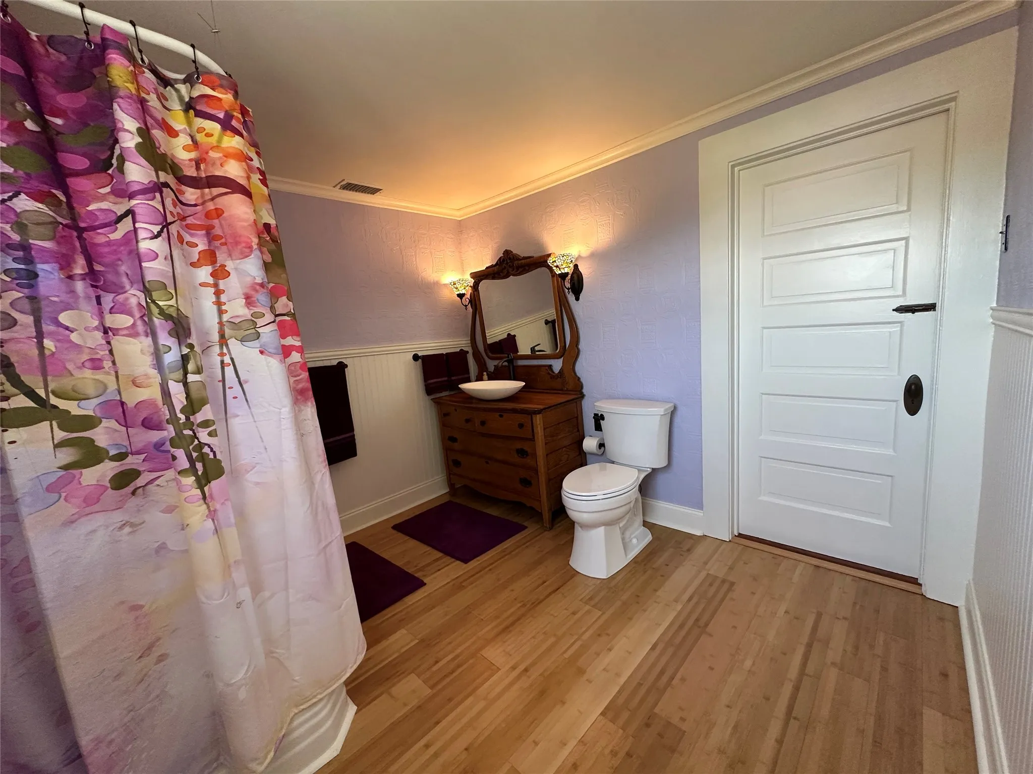 1st upstairs bathroom with
Light wood-finish flooring with white beadboard wainscoting and a white five-panel door