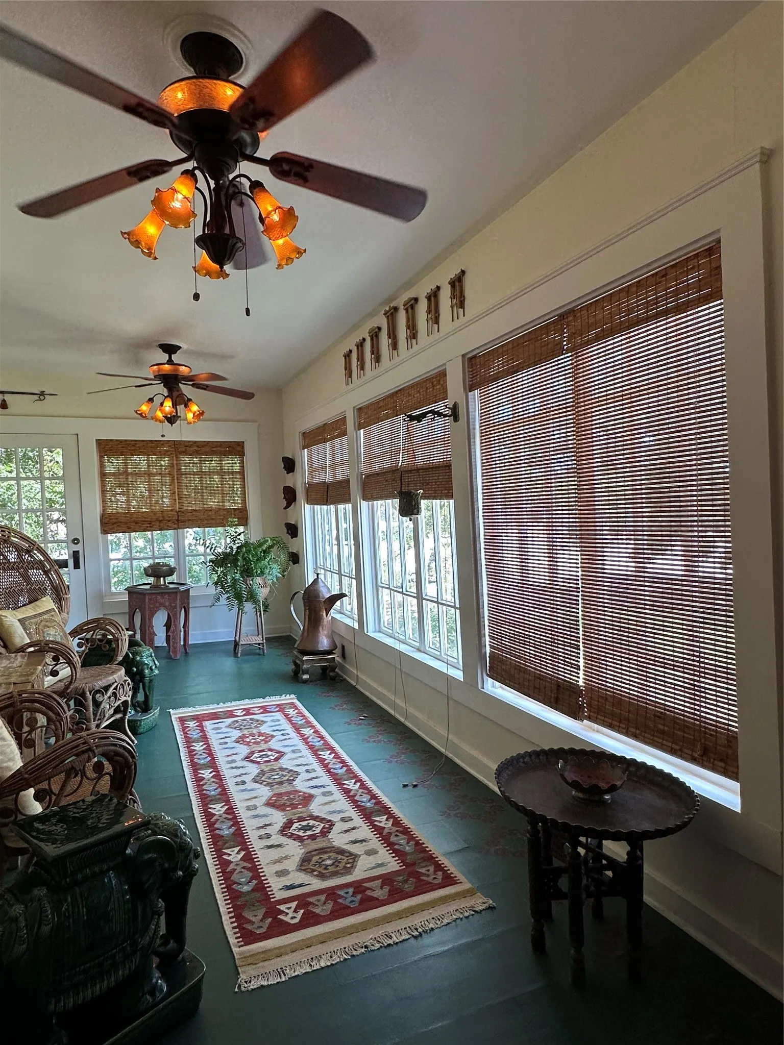 Sunroom with multiple large windows, dark wood-finish flooring, and two ceiling fans with integrated lighting
