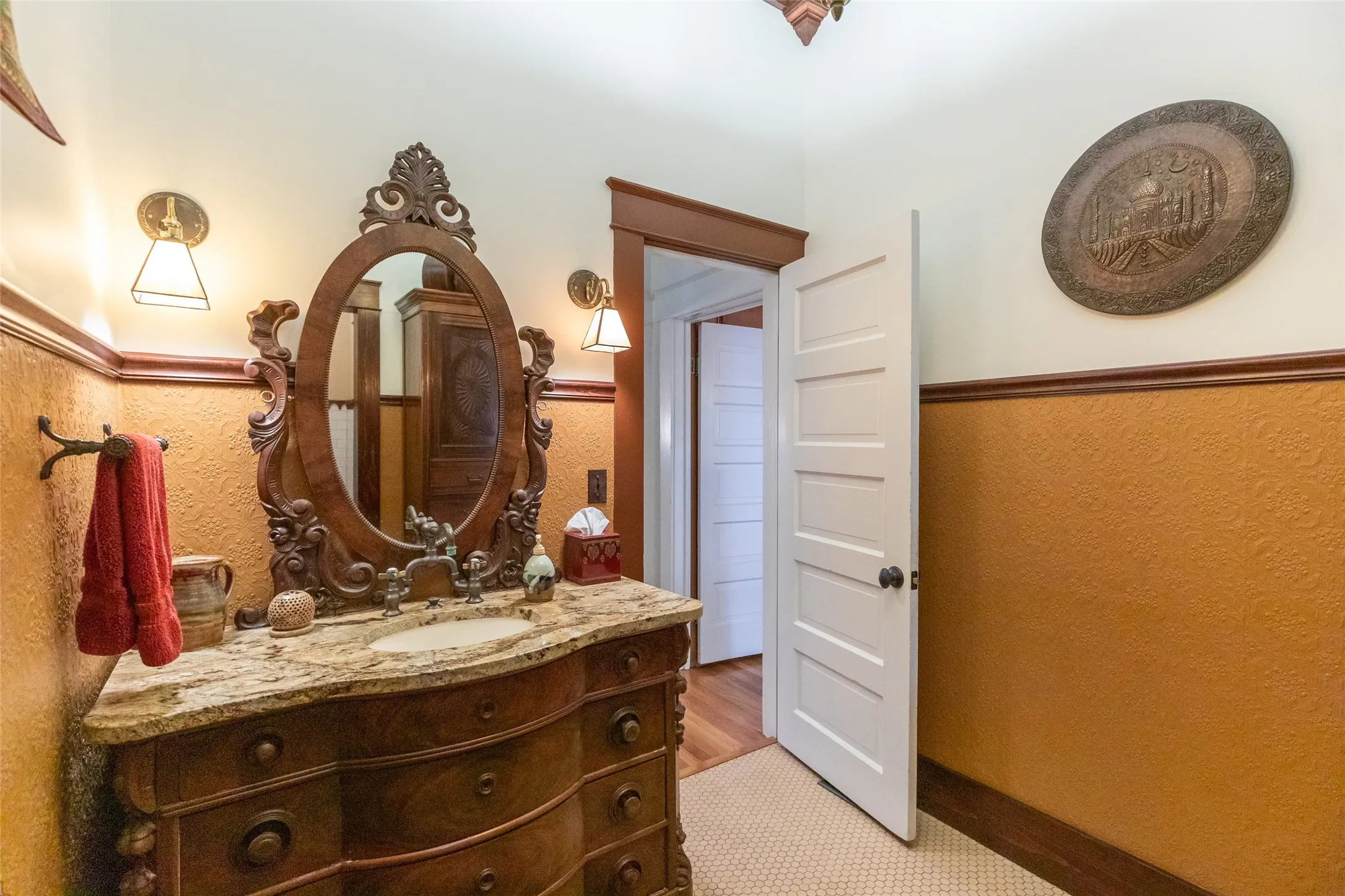 Ornate wood vanity with an oval mirror, stone countertop, and integrated sink