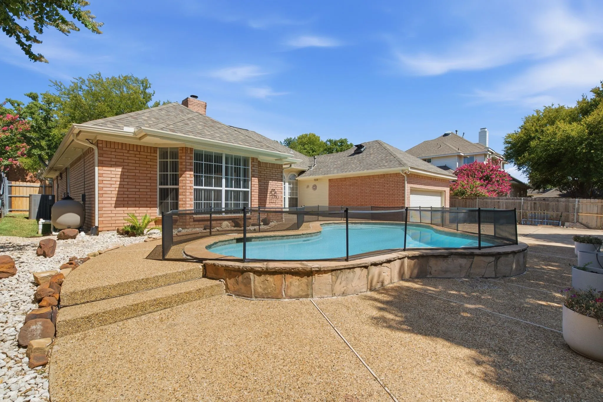 Outdoor swimming pool with a stone surround and safety fencing