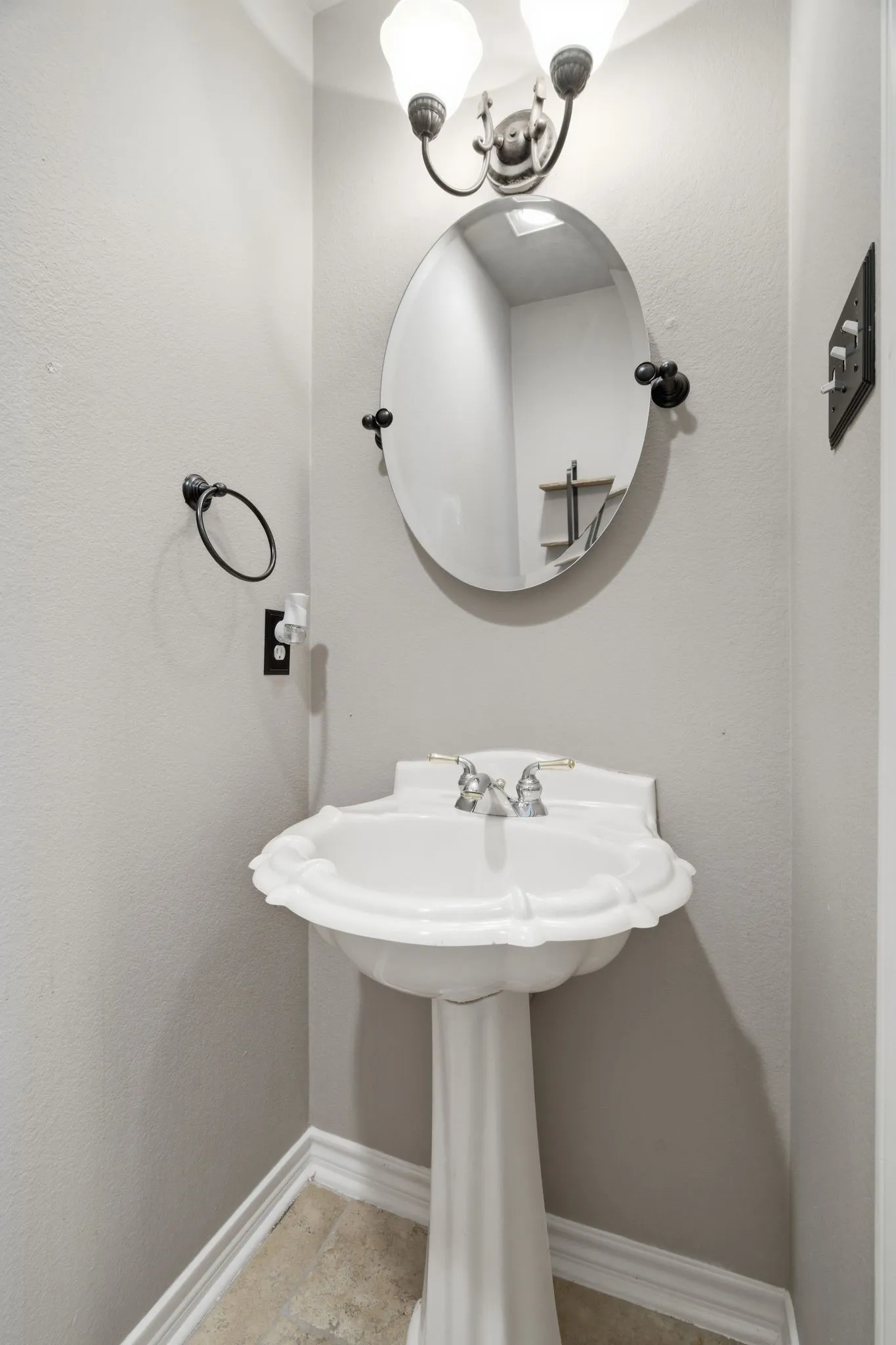 Pedestal sink with a decorative basin, set against light gray walls with white baseboards