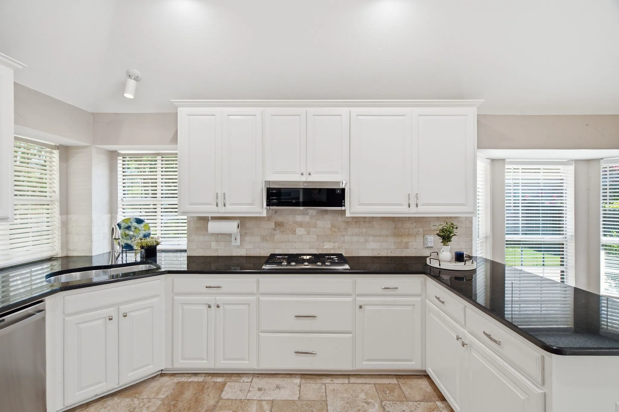 Kitchen featuring white cabinetry, dark countertops, built-in microwave, tile backsplash, and tile flooring