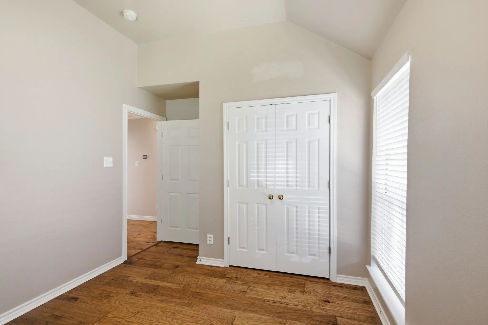 Room featuring wood-finish flooring, neutral wall tones, and white trim