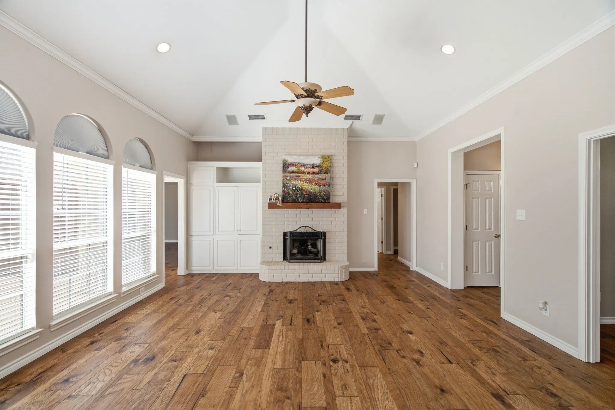 Spacious room featuring wood-finish flooring, a vaulted ceiling with a ceiling fan, and recessed lighting