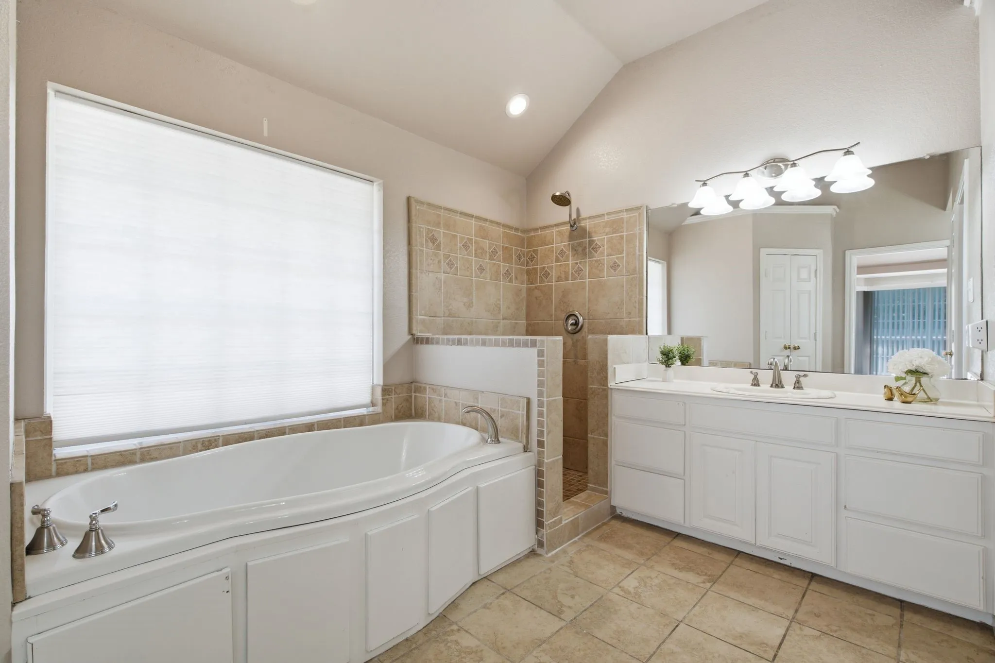 Spacious bathroom featuring a soaking tub, separate tiled shower, and a double vanity with ample storage