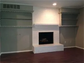 Brick fireplace with a hearth and mantel, flanked by built-in shelving units