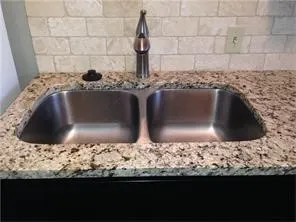 Dual basin stainless steel sink with a high-arch chrome faucet set into a granite countertop