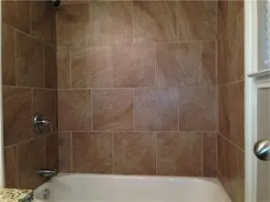Bathtub and shower combination featuring floor-to-ceiling rectangular tile surround and polished chrome fixtures