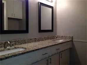 Double vanity with a speckled countertop, undermount sinks, and wall-mounted mirrors