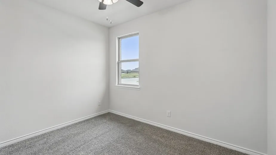 Bright room featuring neutral-toned walls, grey carpet, a ceiling fan, and a double-hung window