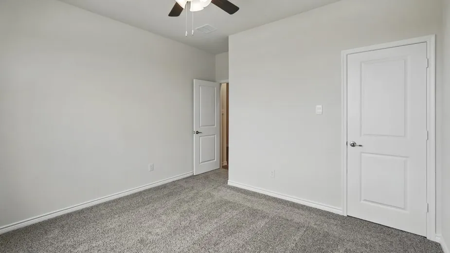 Neutral-toned room featuring a ceiling fan, plush gray carpet, and crisp white baseboards
