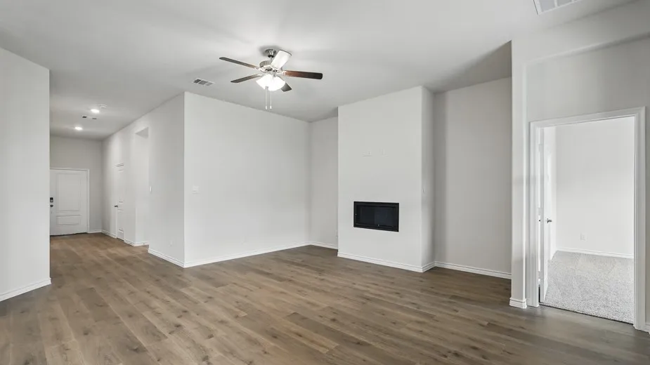 Open-concept living area featuring wood-finish flooring, a contemporary fireplace, and a ceiling fan with integrated lighting