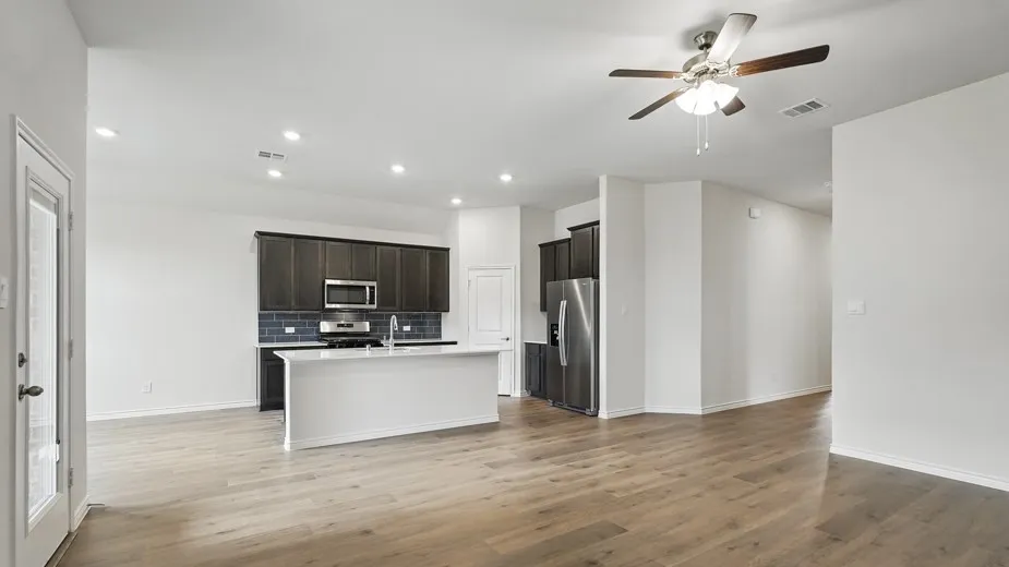 Spacious open-concept living area featuring wood-finish flooring, recessed lighting, and a ceiling fan