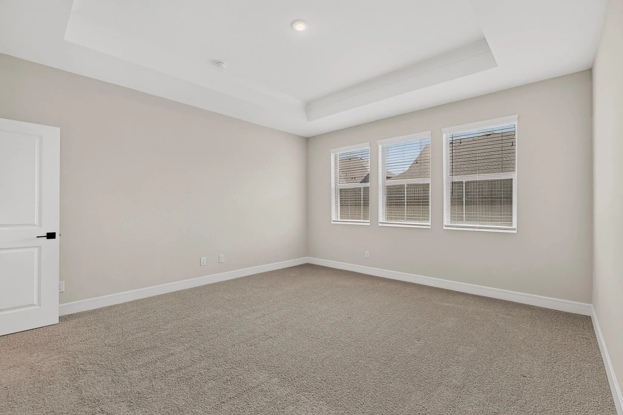 Tray ceiling with crown molding, recessed lighting, carpeted flooring, multiple windows