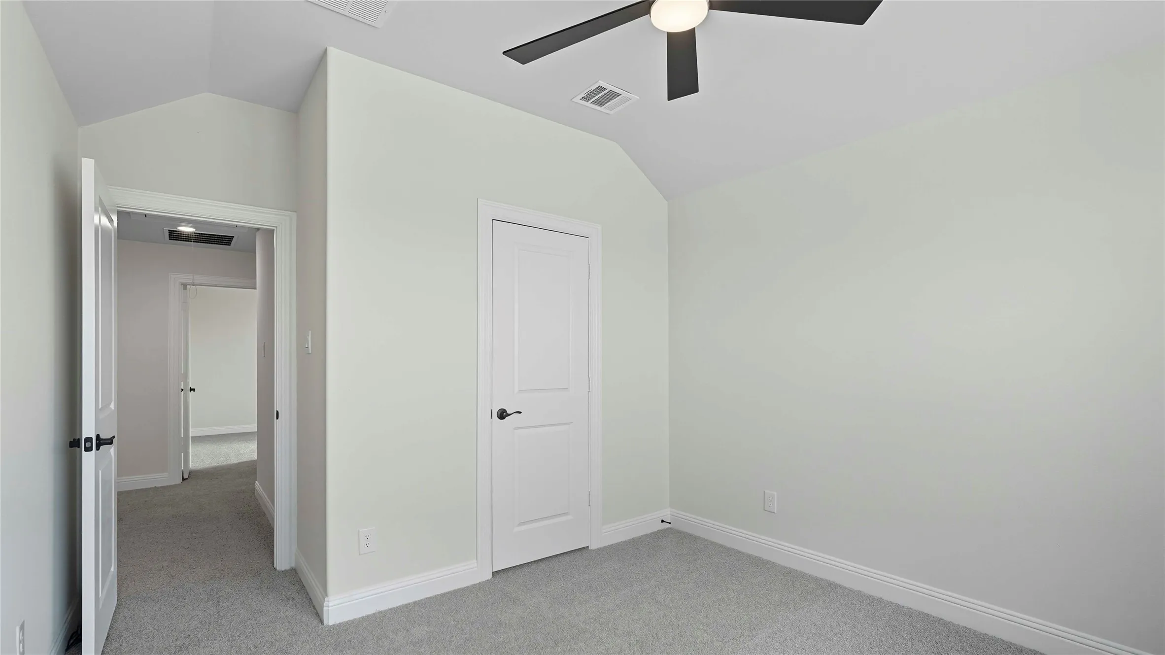 Interior room featuring vaulted ceilings, light gray wall finishes, gray carpeting, a ceiling fan with integrated lighting, and white paneled doors