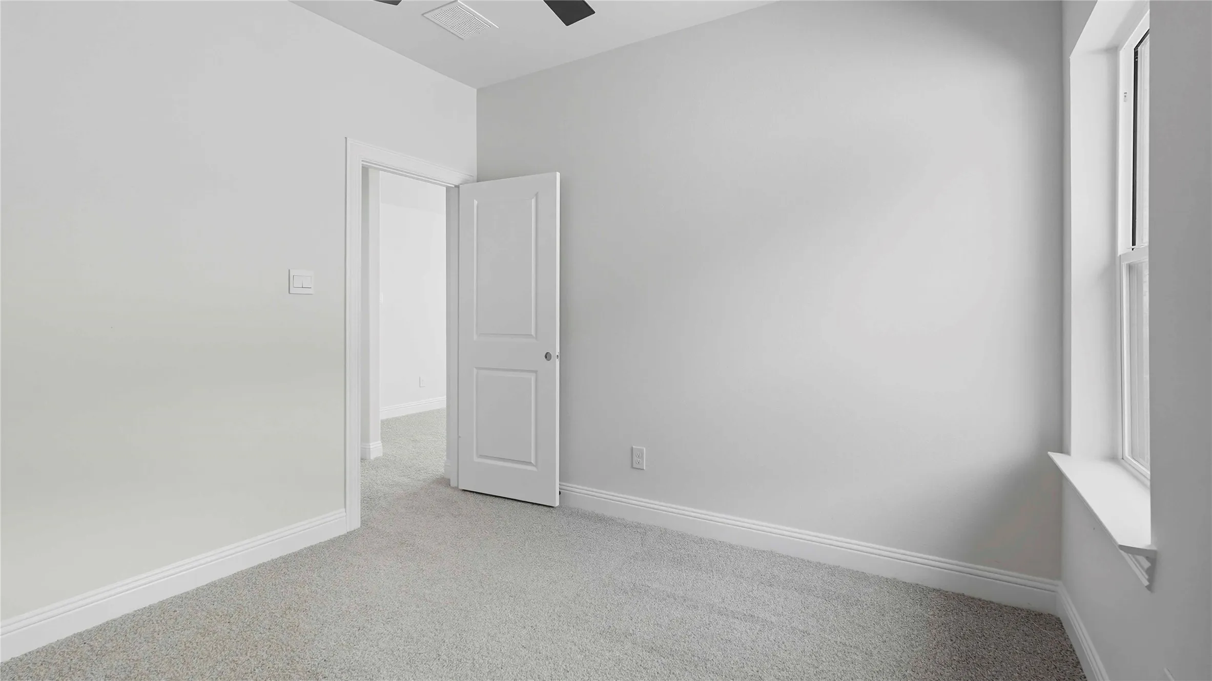 Carpeted room with neutral wall tones, a single window, and a white two-panel door