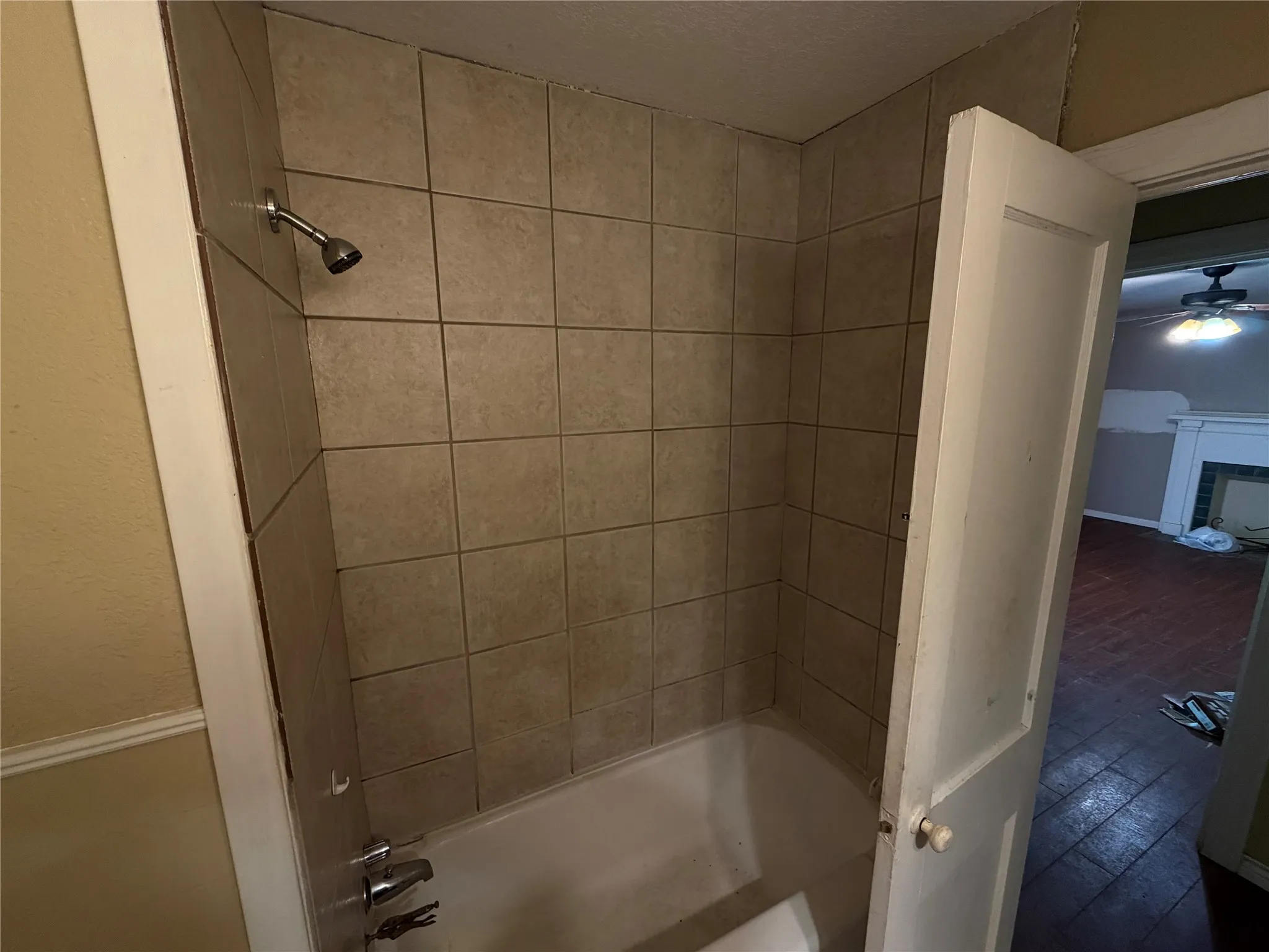 Bathtub and shower combination featuring neutral-toned tile surround and chrome fixtures