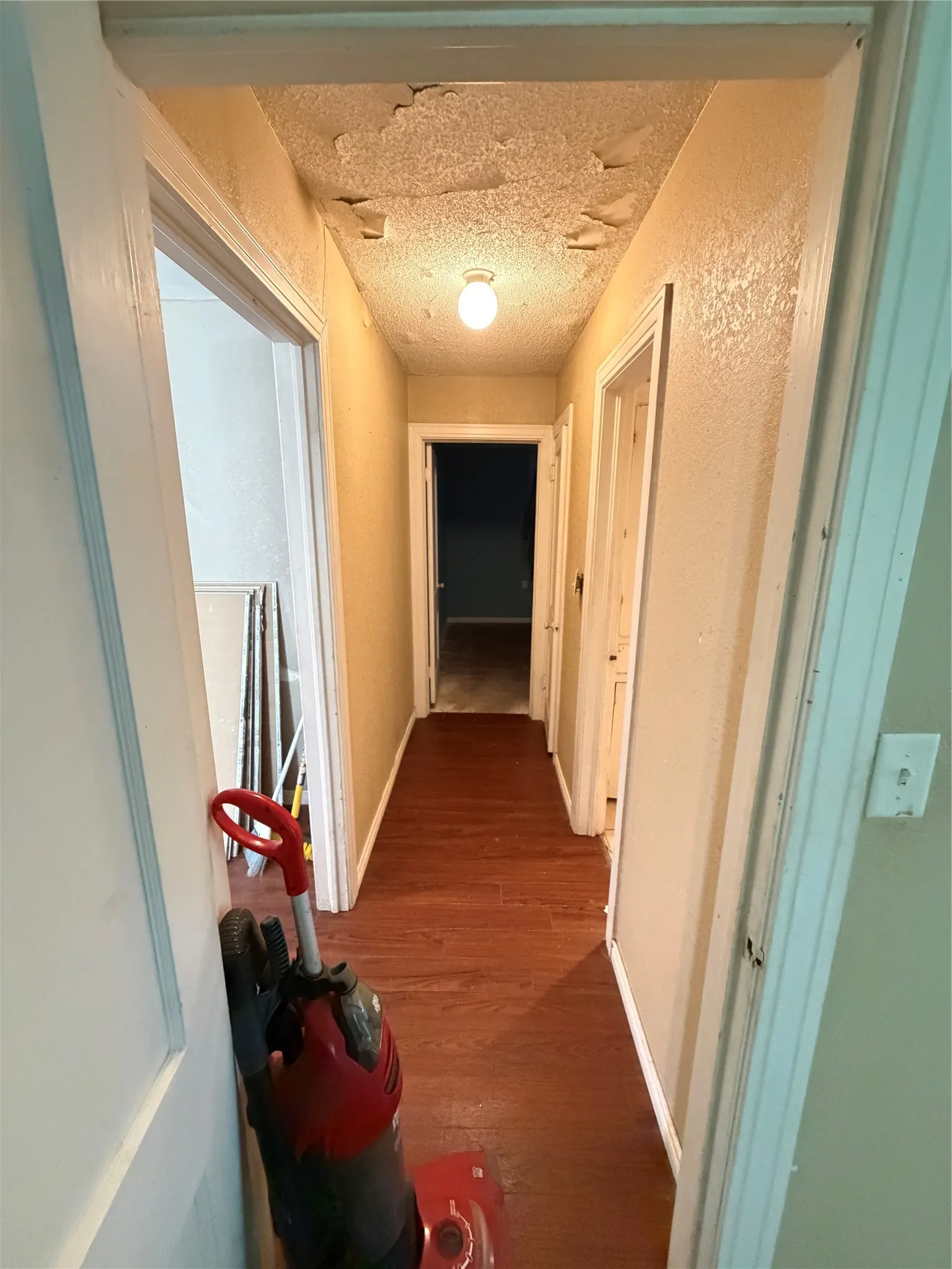 Hallway featuring wood-finish flooring, light-toned walls, and white trim