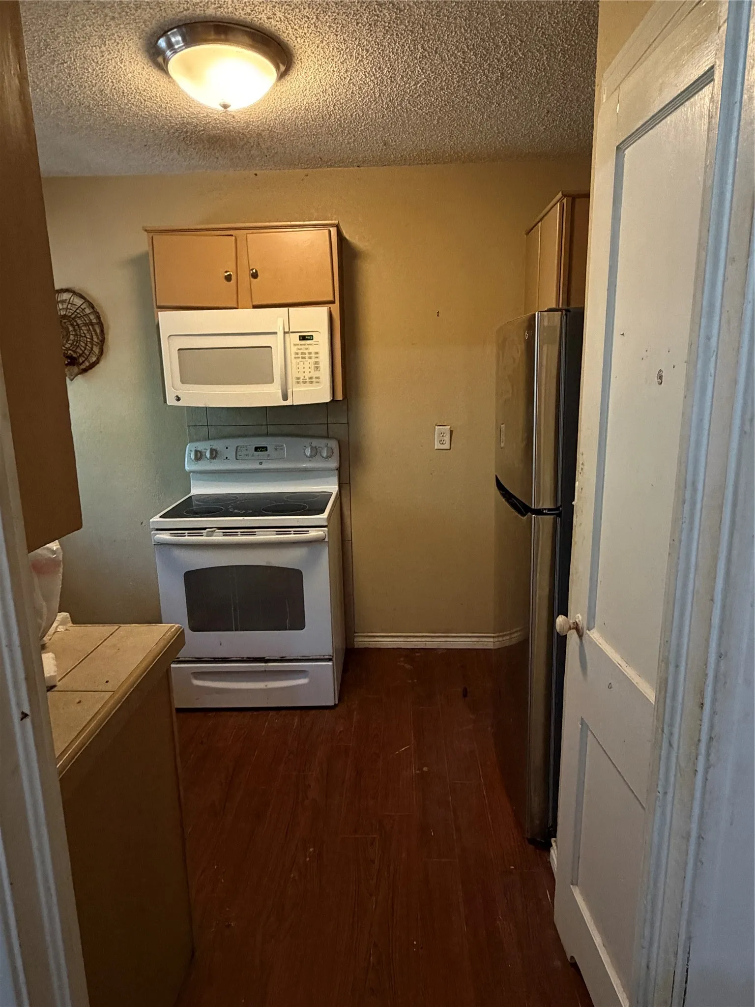 Kitchen featuring wood-finish flooring, wood cabinetry, white electric range, and over-the-range microwave