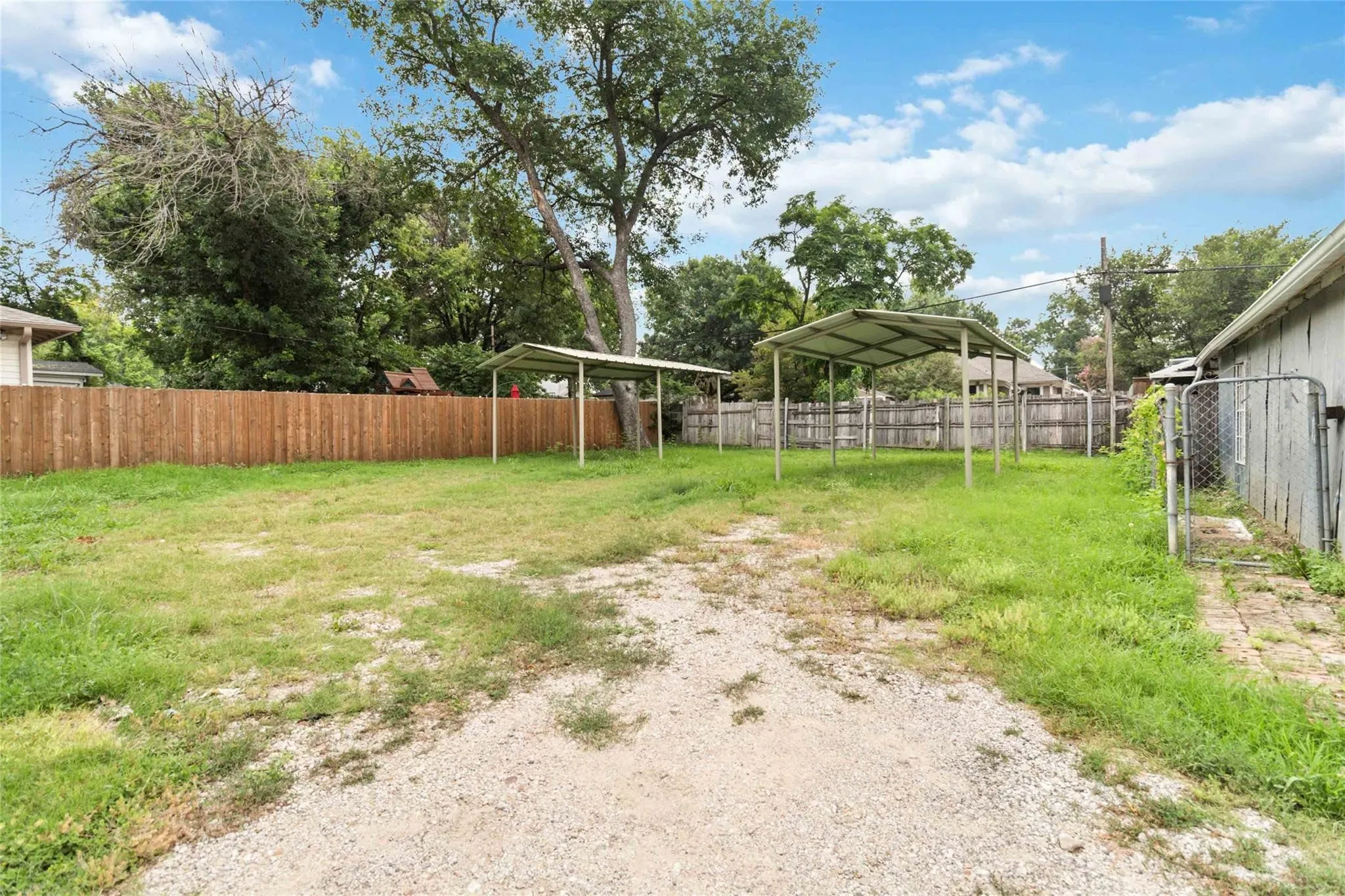 View of yard with a detached carport, fence, and driveway