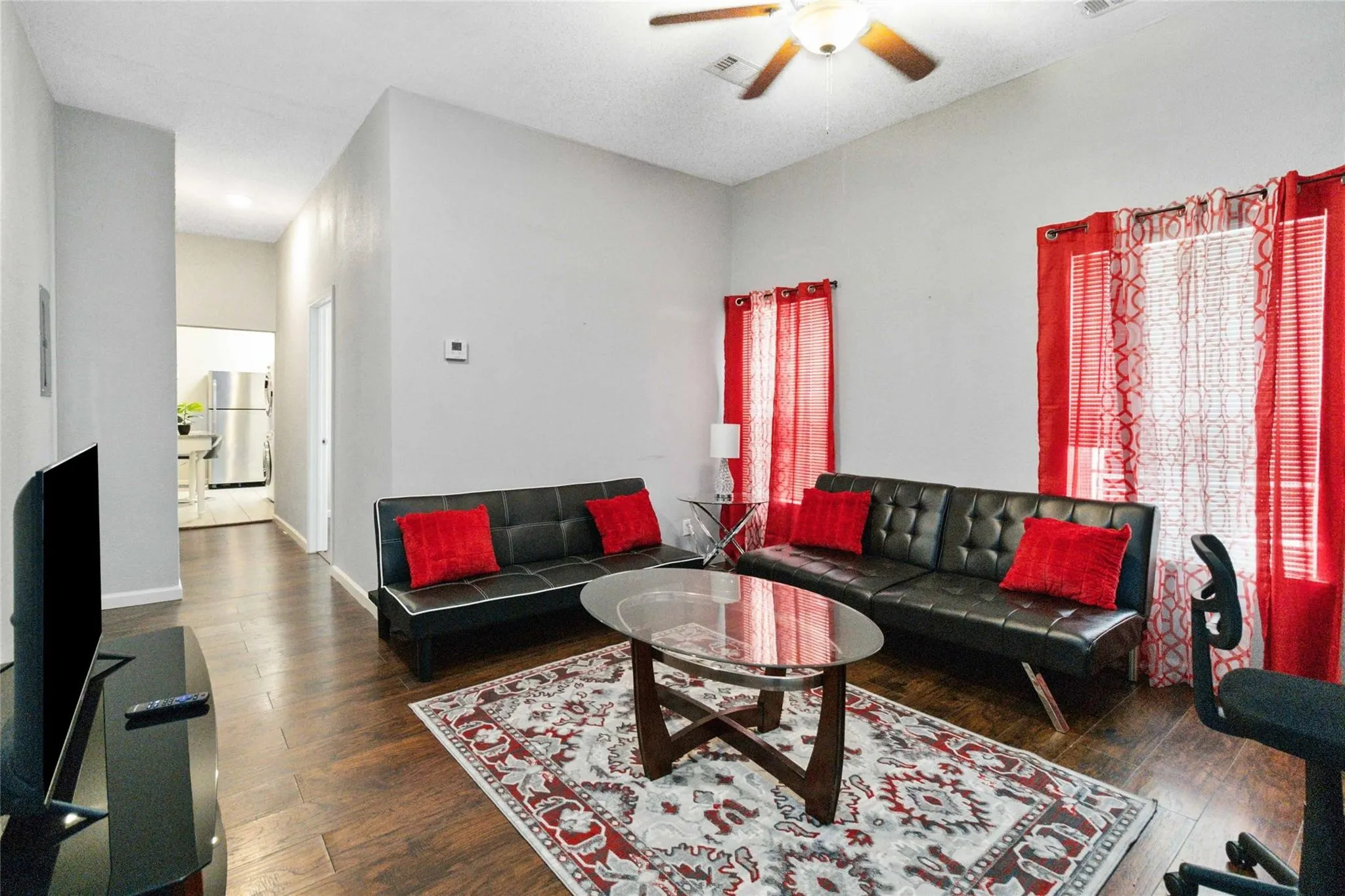 Living room with visible vents, dark wood finished floors, baseboards, and ceiling fan