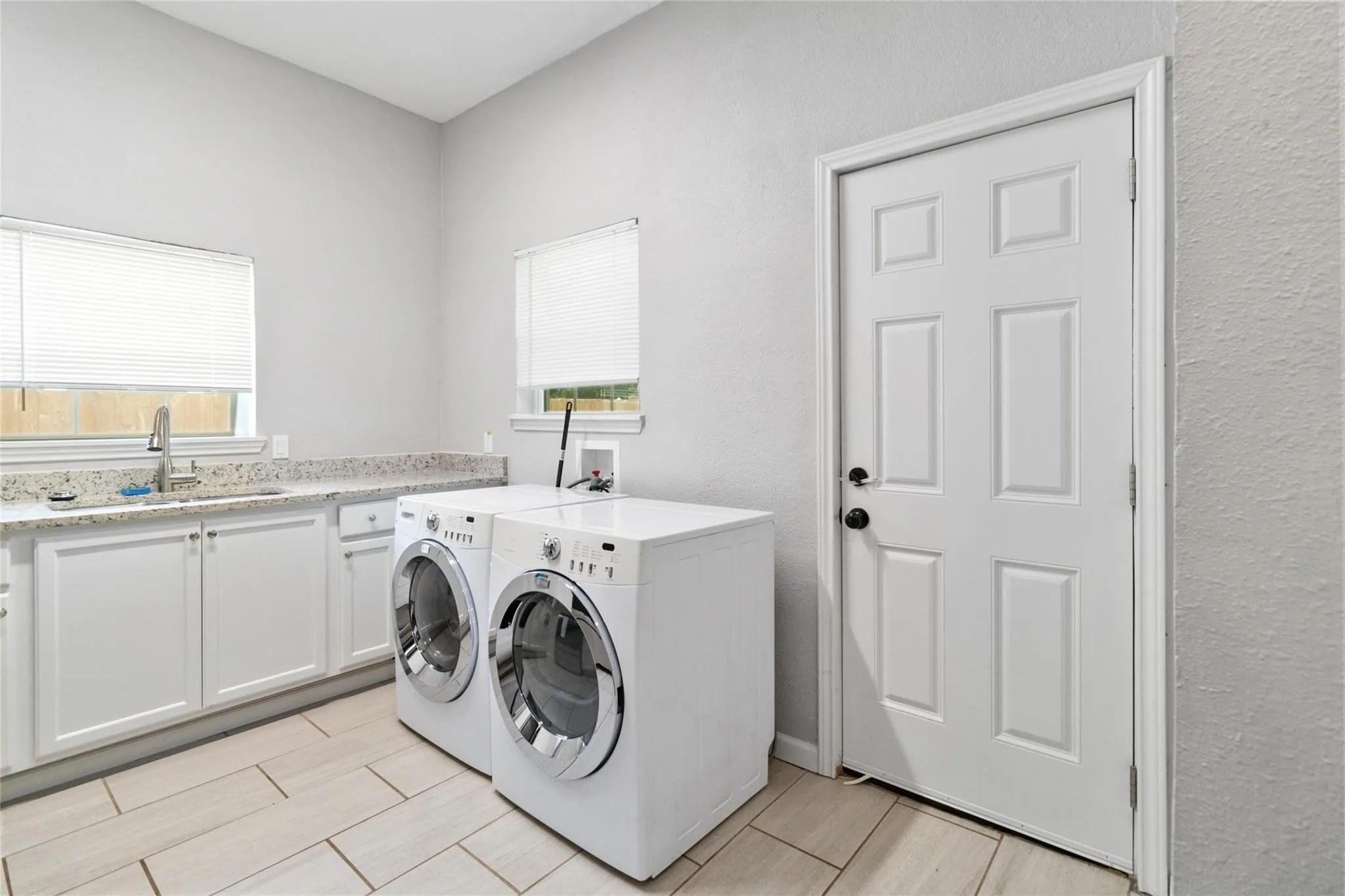 Washroom featuring a healthy amount of sunlight, wood tiled floor, a sink, and washer and dryer