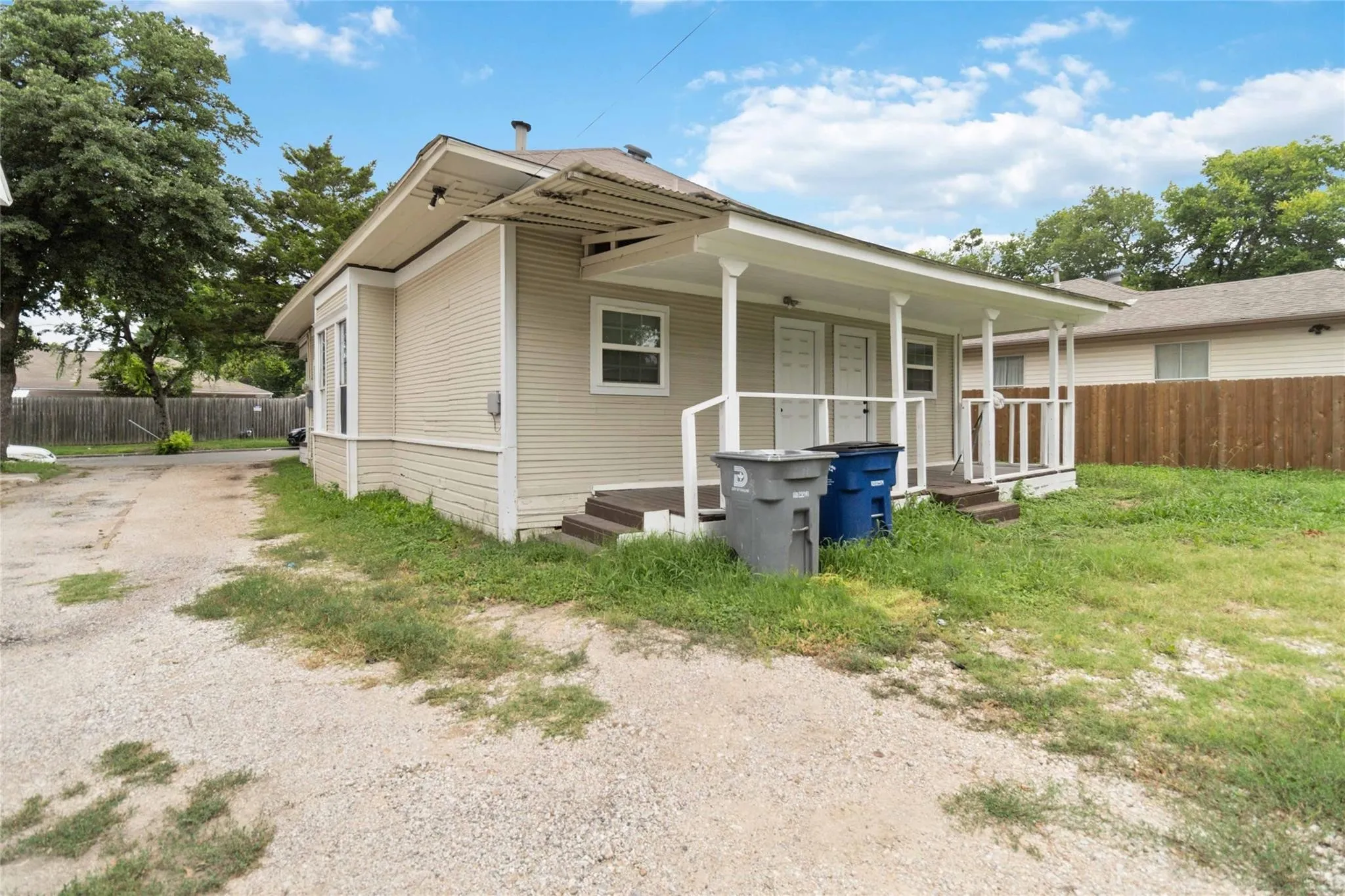 Back of property featuring driveway, covered porch, and fence