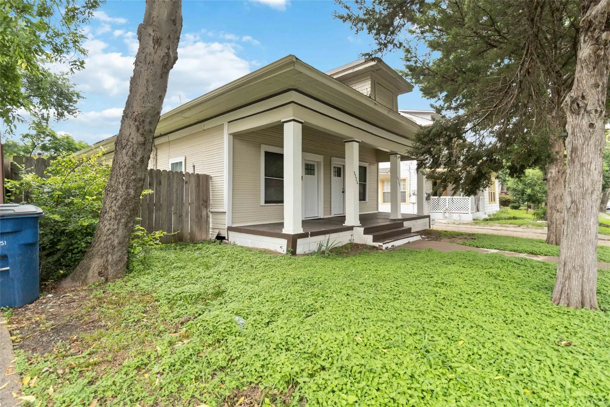 View of front of property with covered porch, fence, and a front lawn