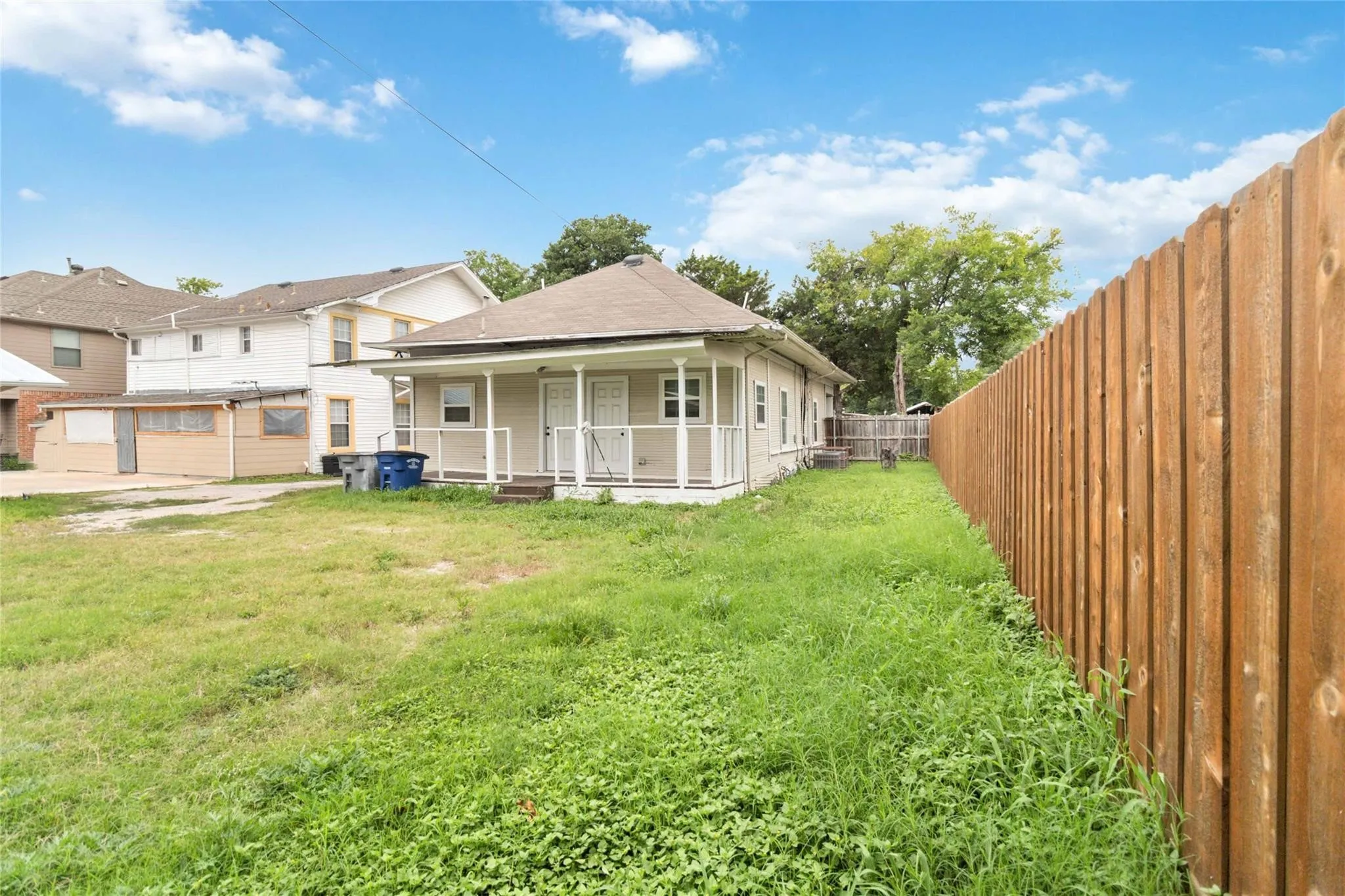 Back of property featuring a porch, a lawn, and a fenced backyard