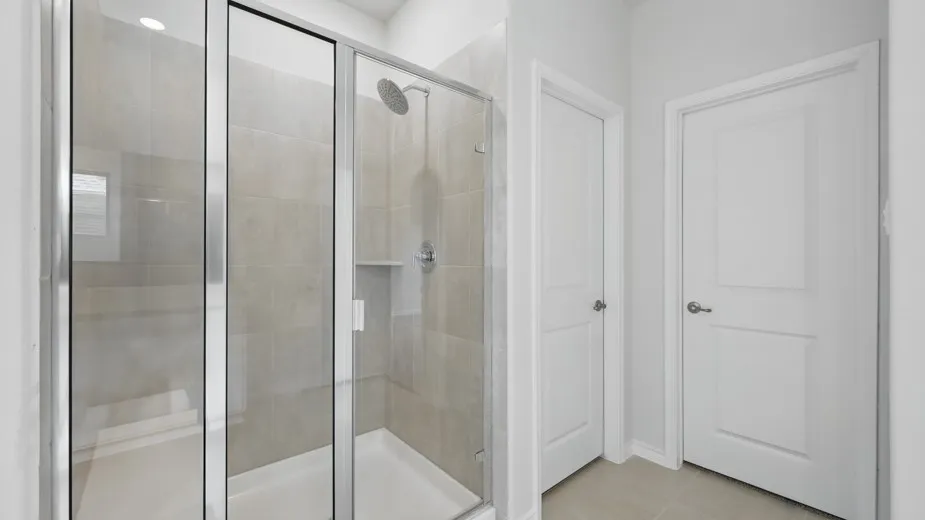 Glass-enclosed shower with a rainfall showerhead, integrated niche, and large format wall tiling