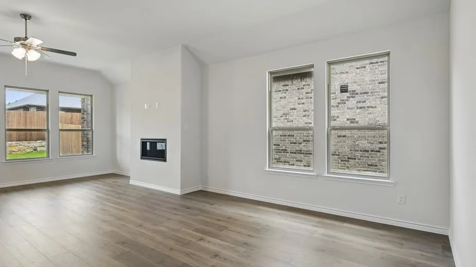 Spacious living area featuring wood-finish flooring, a vaulted ceiling, and multiple windows providing natural light