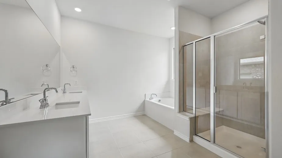 Bright bathroom featuring a double vanity with stone countertops, an undermount tub, a separate glass-enclosed shower, and large format tile flooring