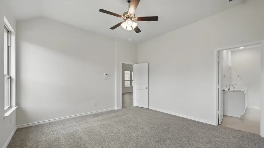 Carpeted room featuring a vaulted ceiling and a ceiling fan with light fixture