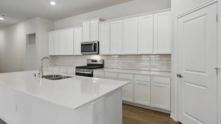 Modern kitchen featuring an expansive island with a double basin stainless steel sink and gooseneck faucet