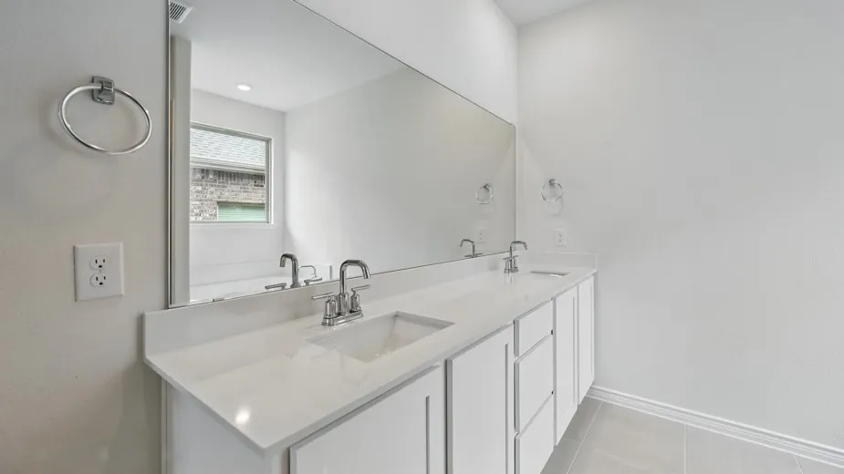 Dual vanity featuring an expansive countertop, integrated sinks, white cabinetry, chrome fixtures, and a full-width mirror
